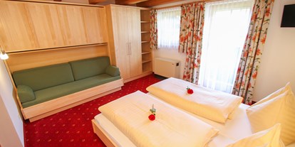 Pensionen - Pinzgau - Schlafzimmer von Uromas Stüberl  zwei bis vier Betten und Sitzcouch und Fernseher mit KTV - Urlaubsparadies Liebmannhof