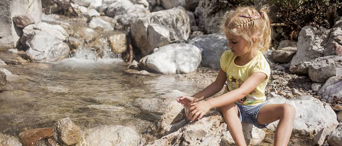 Kind sitzt am kristallklarem Bach am Wilden Kaiser