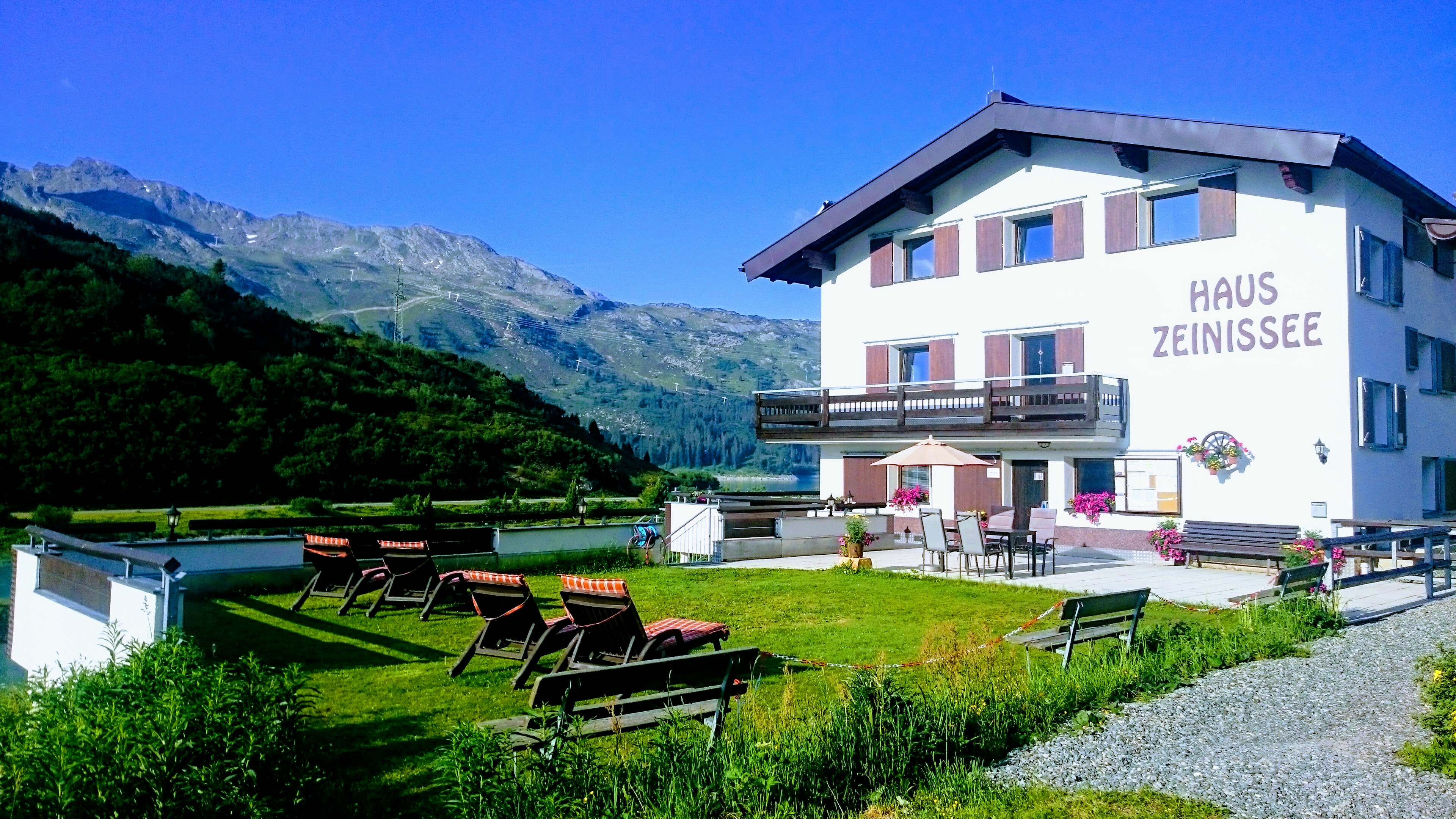 Frühstückspension - Hausansicht mit Liegeweise und Terrasse - im Hintergrund der Zeinissee - Haus Zeinissee