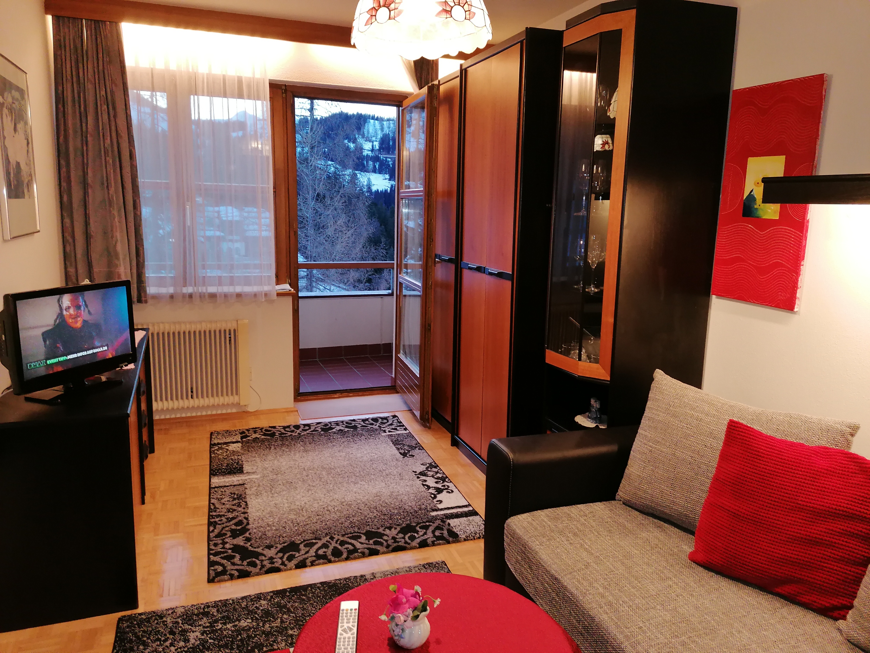 Frühstückspension - Wohnschlafraum mit ausziehbarer Doppelcouch, TV mit integriertem DVD-Player, Wlan und 2 Schränke für Kleidung und 1 Glasvitrine für Gläser aller Art und Balkon nach Westen mit Sitzgarnitur und Sonnenschirm - Appartement Sonja im Haus Carinthia am Nassfeld