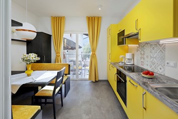 Frühstückspension: Der elegante Wohnbereich mit Küche der gelben Ferienwohnung ist mit allen Annehmlichkeiten ausgestattet.   - Residence Sonnengarten**